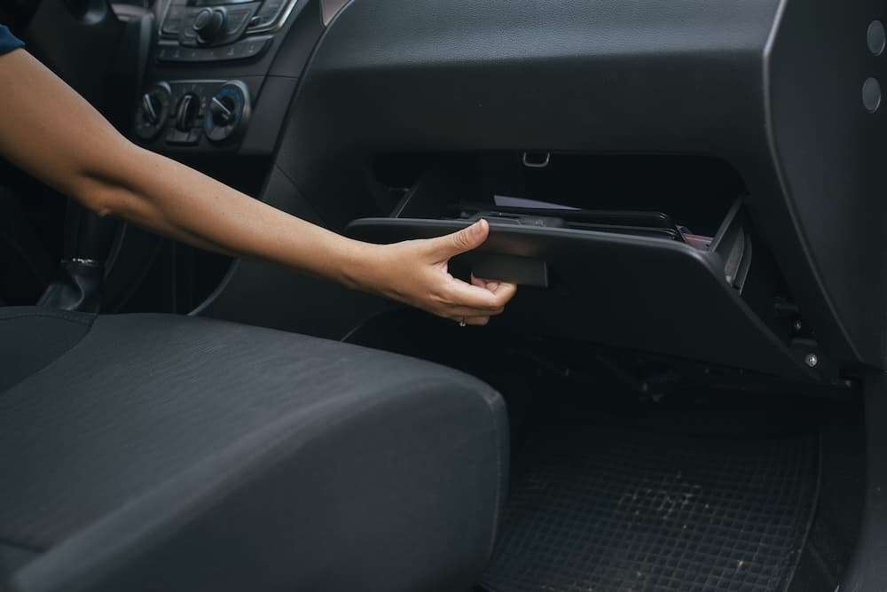 personne ouvrant une boîte à gant dans une voiture