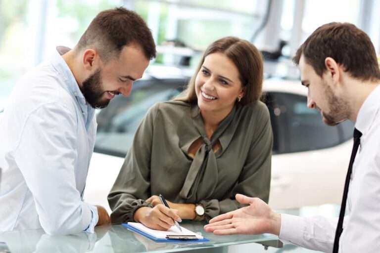 couple souriant signant un contrat de vente de voiture chez un concessionnaire